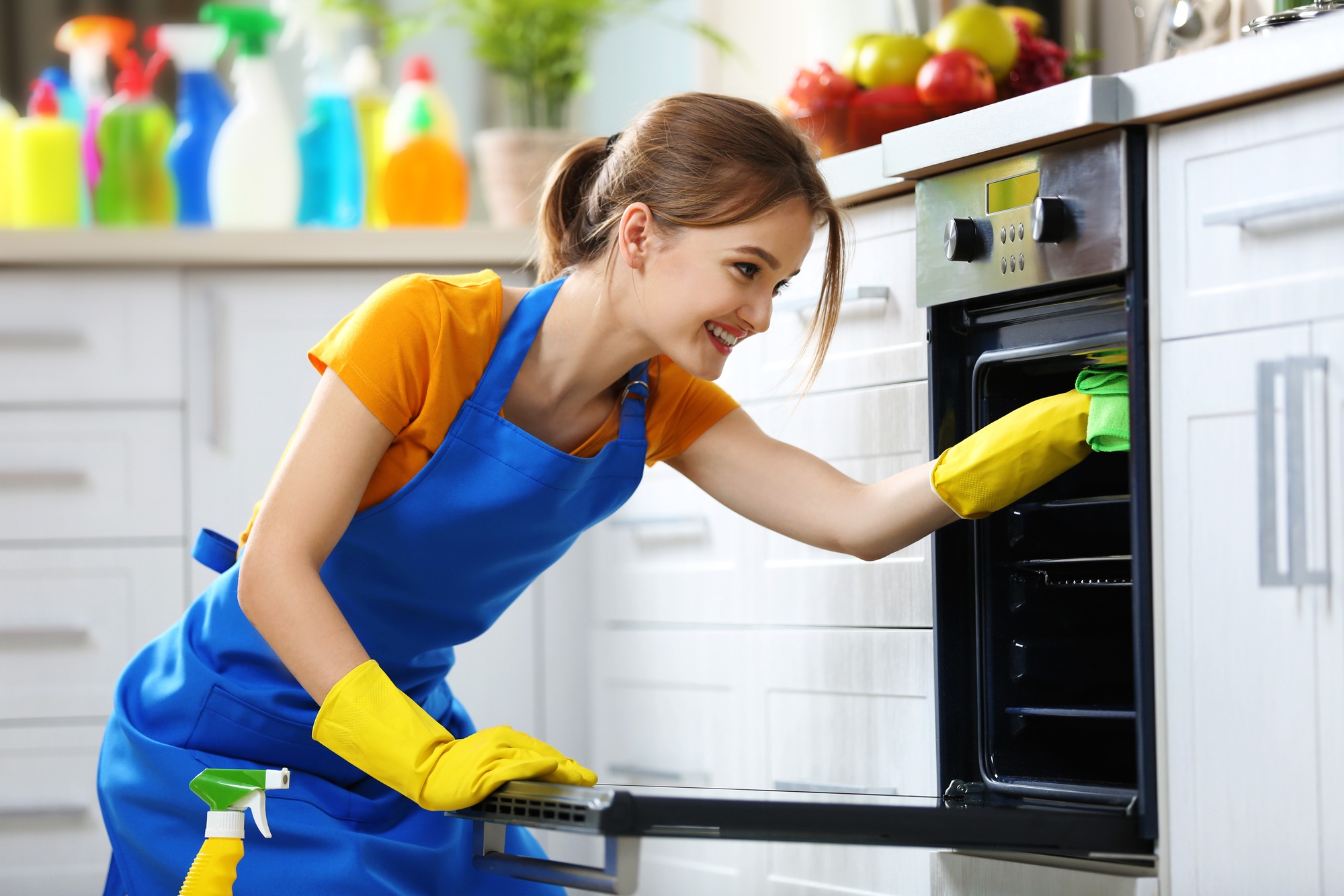 Professional cleaner performing oven deep cleaning service in Naples, FL in a modern kitchen.